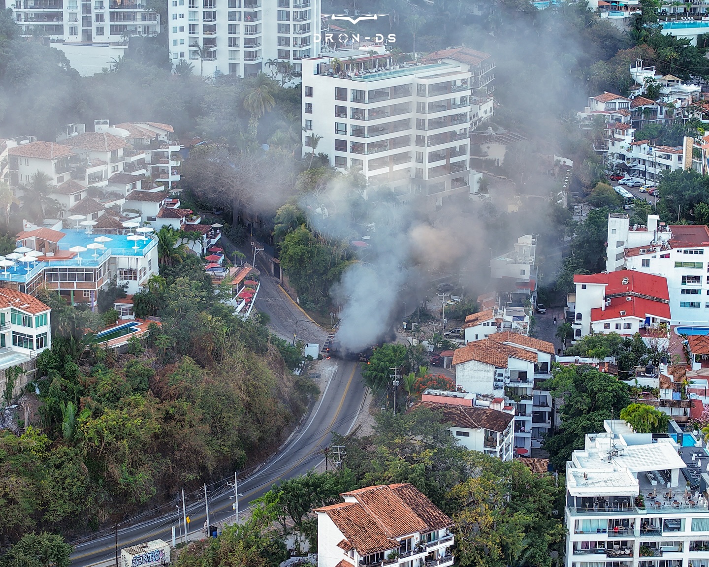 An Aerial shot of a bus on fire on a city street
